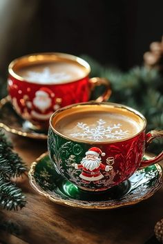 two red and green cups filled with hot chocolate sitting on top of a wooden table