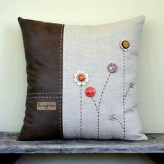 a decorative pillow with buttons on it sitting on a wooden bench next to a wall