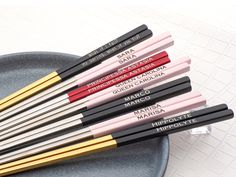 six different colored pencils sitting on top of a black plate next to each other