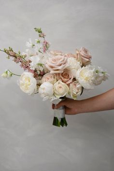 a person holding a bouquet of white and pink flowers