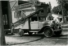 an old truck is parked in front of a house with a ladder on it's back