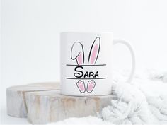 a white coffee mug with the word sara on it and two bunny ears sticking out