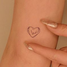 a small tattoo on the back of a woman's left arm that has a heart in it