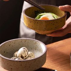 a person holding a bowl with food in it and chopsticks sticking out of it