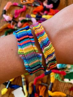 two bracelets that have been made out of yarn sitting on top of a wooden table