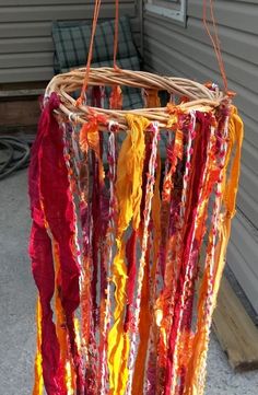 a basket hanging from the side of a house filled with yarn and paper streamers