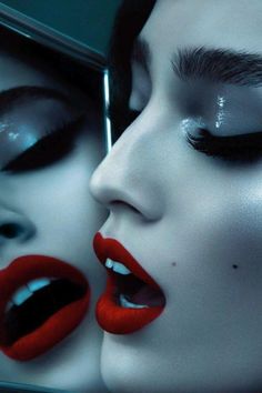 two women with red lips and black make - up are touching each other's noses