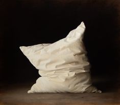 a large white pillow sitting on top of a brown floor next to a black wall