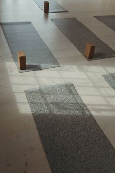 yoga mats with wooden posts on them in the middle of an empty gym floor,