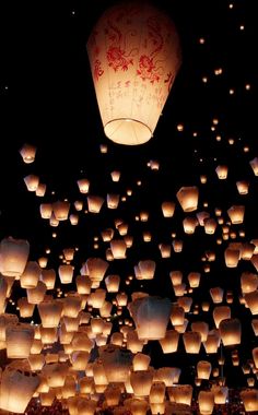 many lit up lanterns floating in the air