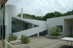 an empty patio with tables and benches on the side of it, next to a white building