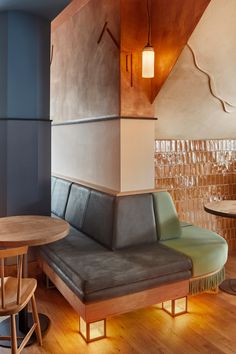 a couch and table in a room with wood flooring on the walls, along with wooden stools