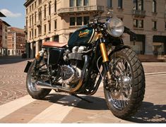 an image of a motorcycle parked on the side of the road with buildings in the background