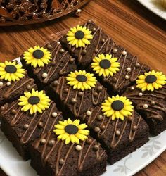 chocolate brownies decorated with sunflowers on top of a white plate and wooden table