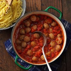 a bowl of spaghetti and meatballs with a spoon in it on a wooden table