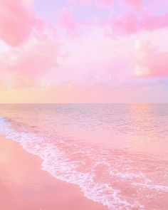 a beach with waves coming in to the shore and pink clouds above it at sunset