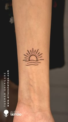 a small sun and wave tattoo on the wrist is shown in black ink, with an outline