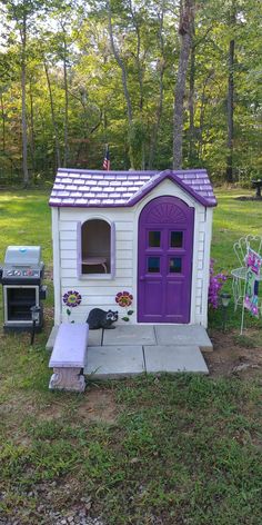 a small purple and white dog house in the middle of a yard with an oven