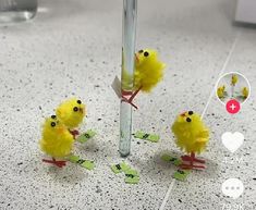 three little yellow chicks sitting on top of each other in front of a tall pole