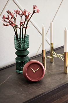 a table topped with candles and a vase filled with flowers next to a candle holder