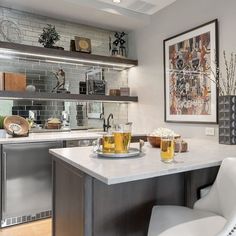 two glasses of beer are sitting on the counter in this modern kitchen with stainless steel appliances and built - in shelving