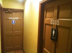 two restroom doors with signs on them in an empty room that says sausage and eggs