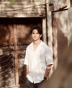 a young man standing in front of an open door with his hands in his pockets