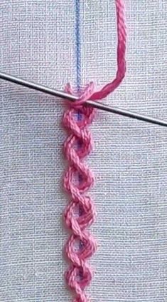 a close up of a pink crochet stitching on a piece of fabric