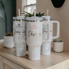 three white coffee mugs sitting on top of a wooden table