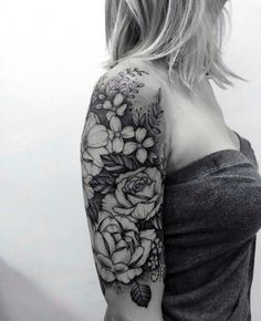 a woman's arm with flowers and leaves tattooed on the back of her shoulder