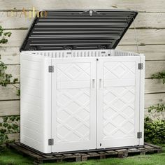 a white storage shed sitting in the grass