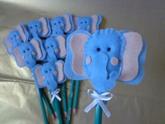 a bunch of small blue elephants on top of green sticks with white ribbons around them