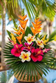 a basket filled with lots of flowers on top of a table next to palm trees