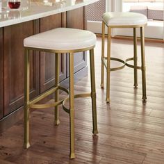 two white stools sitting next to each other in a kitchen near a counter top