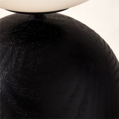 a black and white lamp is sitting on top of a round object with a circular base