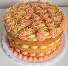 a three layer cake with pink icing and flowers on top is sitting on a white plate