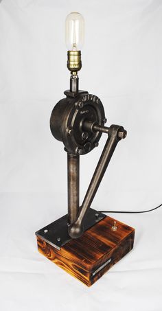 an old fashioned steam engine lamp on a wooden base with a light bulb attached to it