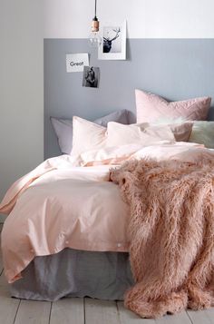 a bed with pink and grey sheets in a bedroom next to a white rug on the floor