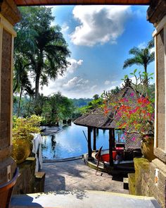 a gazebo sitting on top of a lush green hillside next to a pool surrounded by trees