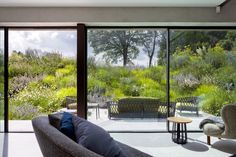 a living room with large glass doors leading to the outside patio and seating area that overlooks a lush green hillside