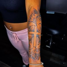 a woman's arm with a cross tattoo on it and flowers in the middle