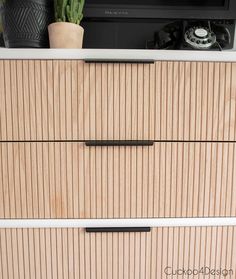 a wooden dresser with two drawers and a television on the top shelf above it, next to a potted cacti