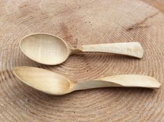 two wooden spoons sitting on top of a tree stump