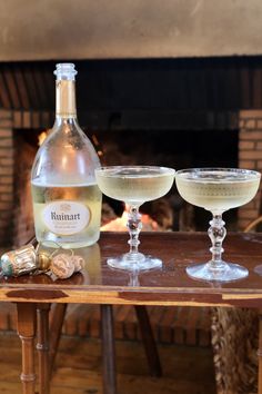 two wine glasses sitting on top of a wooden table next to a bottle of wine