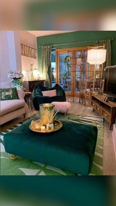 a living room filled with furniture and a flat screen tv sitting on top of a green ottoman