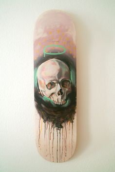 a skateboard with a skull painted on it's side and dripping paint all over the bottom