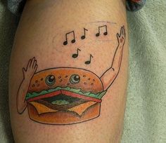 a tattoo on the leg of a person with a hamburger and music notes above it