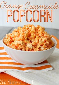 orange creamsice popcorn in a white bowl on an orange and white tablecloth