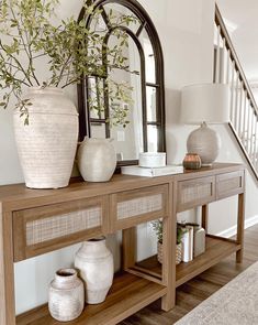 a wooden table topped with vases next to a mirror and bannister on top of it