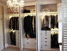 an organized closet with white drawers and chandelier